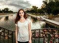 Cute woman on bridge with love locks on fence looking at camera Royalty Free Stock Photo