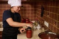 Pretty woman chef using seamer or special seaming key, closes lids of jars with freshly canned tomato sauce or passata Royalty Free Stock Photo