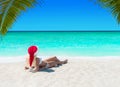 Cute woman in Christmas Santa hat sunbathing at tropical sandy o Royalty Free Stock Photo