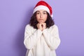 Cute Woman With Dark Wavy Hair Posing Dresses Warm Whiete Sweater And Santa Claus Cap, Female Looking At Camera With Pouty Lips