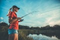 Cute woman is fishing with rod on lake Royalty Free Stock Photo