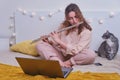 Cute woman flutist plays a musical instrument. Online learning, music lessons via laptop