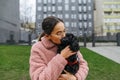 Cute woman in glasses and a pink coat stands on the street with a puppy in her arms, hugging and kissing a pet. Attractive lady Royalty Free Stock Photo