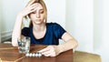 Cute woman holding her head and looking at a glass of water and pills. To feel bad. Coronavirus disease, covid-19. Feel sick Royalty Free Stock Photo