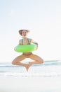 Cute woman holding a rubber ring while jumping on the beach Royalty Free Stock Photo