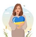 Cute woman hugs heart in the color of the Ukrainian flag. The concept of love for Ukraine and support for the country