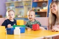 Cute woman and kids playing educational toys at kindergarten or nursery room Royalty Free Stock Photo