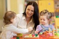 Cute woman and kids playing educational toys at kindergarten or nursery room Royalty Free Stock Photo