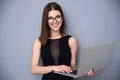 Cute woman with laptop standing over gray background Royalty Free Stock Photo