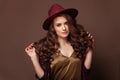 Cute woman with long brown curly hair posing on brown background Royalty Free Stock Photo