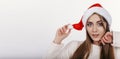 Cute woman looking at camera and toching her christmas hat