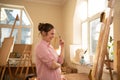 Cute woman paints on canvas in an art workshop. Artist creating picture. Art school or studio. Work with paints, brushes Royalty Free Stock Photo