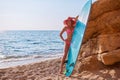 Cute woman posing with surfboard on seashore. Smiling girl in bright bikini on beach. Summer holidays and surfing idea Royalty Free Stock Photo