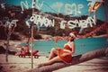 Cute woman in red dress, sunglasses and santa hat sitting on palm tree at exotic tropical beach. Holiday concept for New Royalty Free Stock Photo