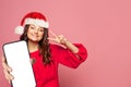 Cute woman in red Santa hat showing smartphone with empty white screen display for new Application on bright pink wall background Royalty Free Stock Photo