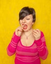 Cute woman with short hair dressed in a pink cozy sweater plays with a large long roll of bubble gum