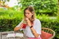 Cute woman sitting on a chair in summer garden, drinking ice tea and writing in a notebook Royalty Free Stock Photo