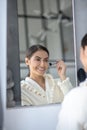 Cute woman sitting at the mirror doing makeup and smiling