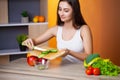 Cute woman slices cucumber for diet salad. Royalty Free Stock Photo