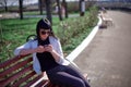 Cute Woman with Sunglasses and Long Hair is Using Mobile Device Enjoying Sunbeams and Warm Day Outdoors. Portrait of Smiling Royalty Free Stock Photo