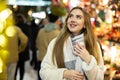 Cute woman walking through evening Christmas market on city street
