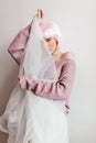 Cute wonderful girl with pink hair hiding face behind white cloth. Studio portrait of glamorous female model in shiny