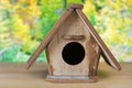 Cute wooden bird house with entrance on wood floor with blurred