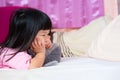 Cute 4 year old Asian girl lying prone on the mattress. Little kid holding her chin. Touchy child, bad mood, unhappy children.