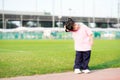 Cute 4 year old Asian girl standing for exercise. Child embraces his arms across the head to opposite side of the head.