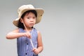 Cute 4-5 year old girl is attire, she is wearing cream colored hat and is using her two hands to adjust the position neckband
