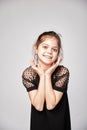 A cute 10-year-old model with an oriental appearance expresses joy dressed in a black dress, advertising clothes. Royalty Free Stock Photo