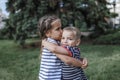 Cute 7-8 years girl hugging her smaller brother during their summer walking in the park