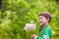 Cute 4 years old boy with dandelion outdoors at sunny summer day.