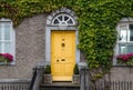 Cute yellow entrance door in a house braided with ivy