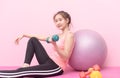 Cute younf girl lifting dumbbell on pink background