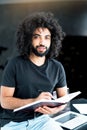 Cute young african american student holds a notebook in his hands and writes in it while looking at the camera Royalty Free Stock Photo