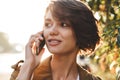 Cute young amazing woman walking outdoors in park in beautiful spring day talking by mobile phone Royalty Free Stock Photo