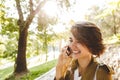 Cute young amazing woman walking outdoors in park in beautiful spring day talking by mobile phone Royalty Free Stock Photo