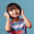 A cute young asian boy enjoying listening to music from his wireless headphones. Adorable Chinese kid smiling and Royalty Free Stock Photo