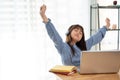 A cute young Asian girl is feeling tired, stretching her arms while studying online at home