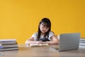 A cute young Asian girl focusing on reading a book at her study table. elementary school student Royalty Free Stock Photo