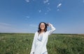 A cute young Asian woman with glasses smiles against a background of blue sky and green dense grass Royalty Free Stock Photo