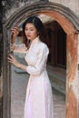 Cute young Asian woman standing at arched passage of ancient building