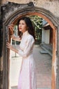 Cute young Asian woman standing at arched passage of ancient building