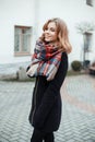 Cute young attractive woman in a stylish winter warm coat in black gloves with a fashionable vintage checkered woolen scarf Royalty Free Stock Photo