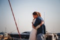 Cute young beautiful couple hugging at pier at port with small yachts, hipsters