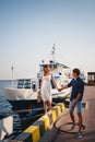 Cute young beautiful couple at pier at port with small yachts, hipster, happy smiling outdoor portrait Royalty Free Stock Photo