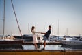 Cute young beautiful couple at pier at port with small yachts, hipster, happy smiling outdoor portrait Royalty Free Stock Photo