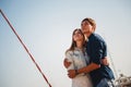 Cute young beautiful couple at pier at port with small yachts looking up at sky, hipster, happy smiling outdoor portrait Royalty Free Stock Photo