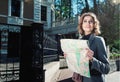 Cute young beautiful curly smiling caucasian travelling woman reading a map